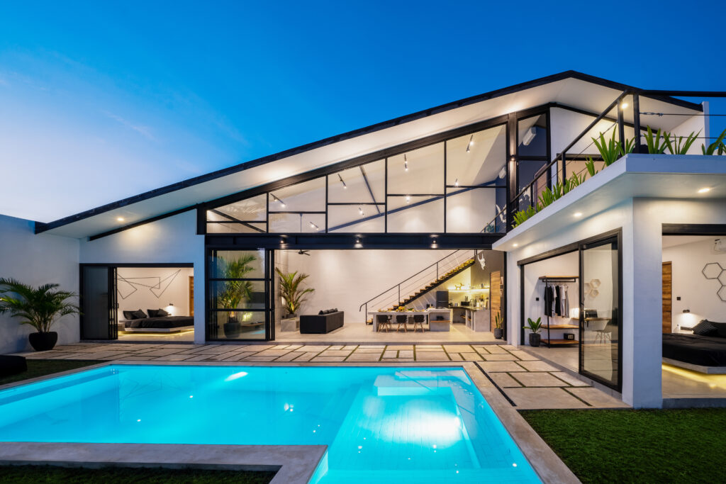 Exterior view of back patio and pool in a luxury setting at night.